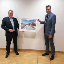 Der Geschäftsführer Dirk Flege (links) überreicht Staatssekretär Mayer das Bild vom Bahnhof des Jahres